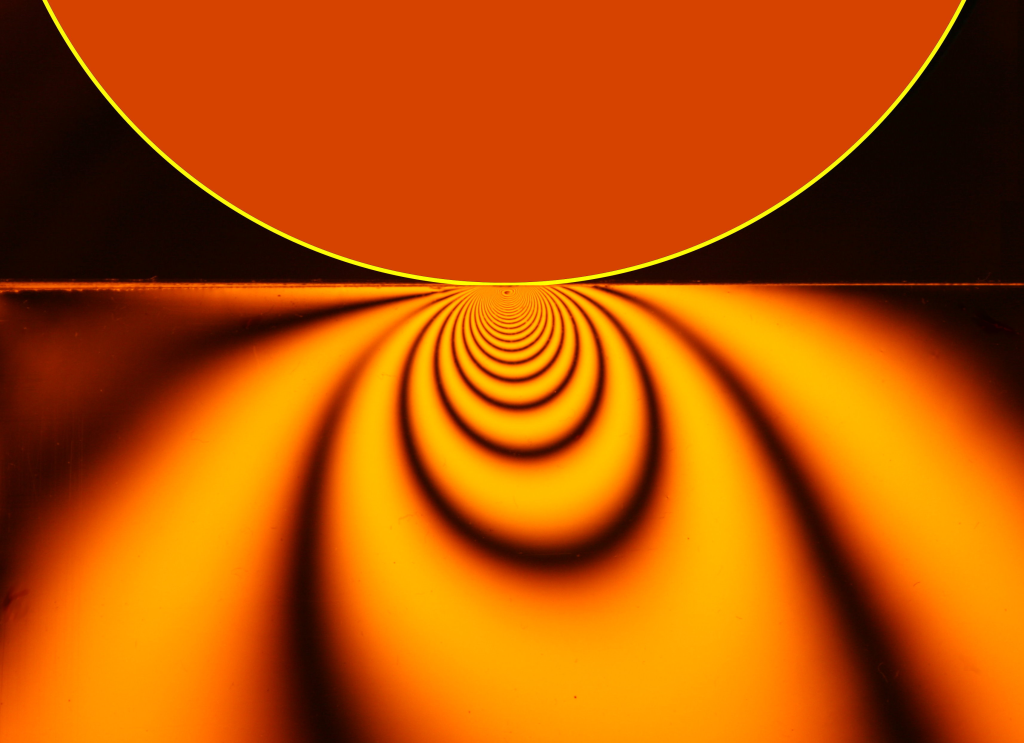 Photoelastic visualization of rolling contact stresses due to a cylinder rolling on a flat surface.