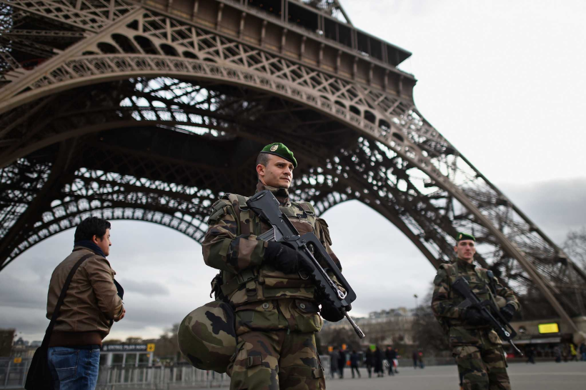 French troops stand guard at the Eiffel Tower, increasing regional security following the November 13th, 2015 Paris attacks.